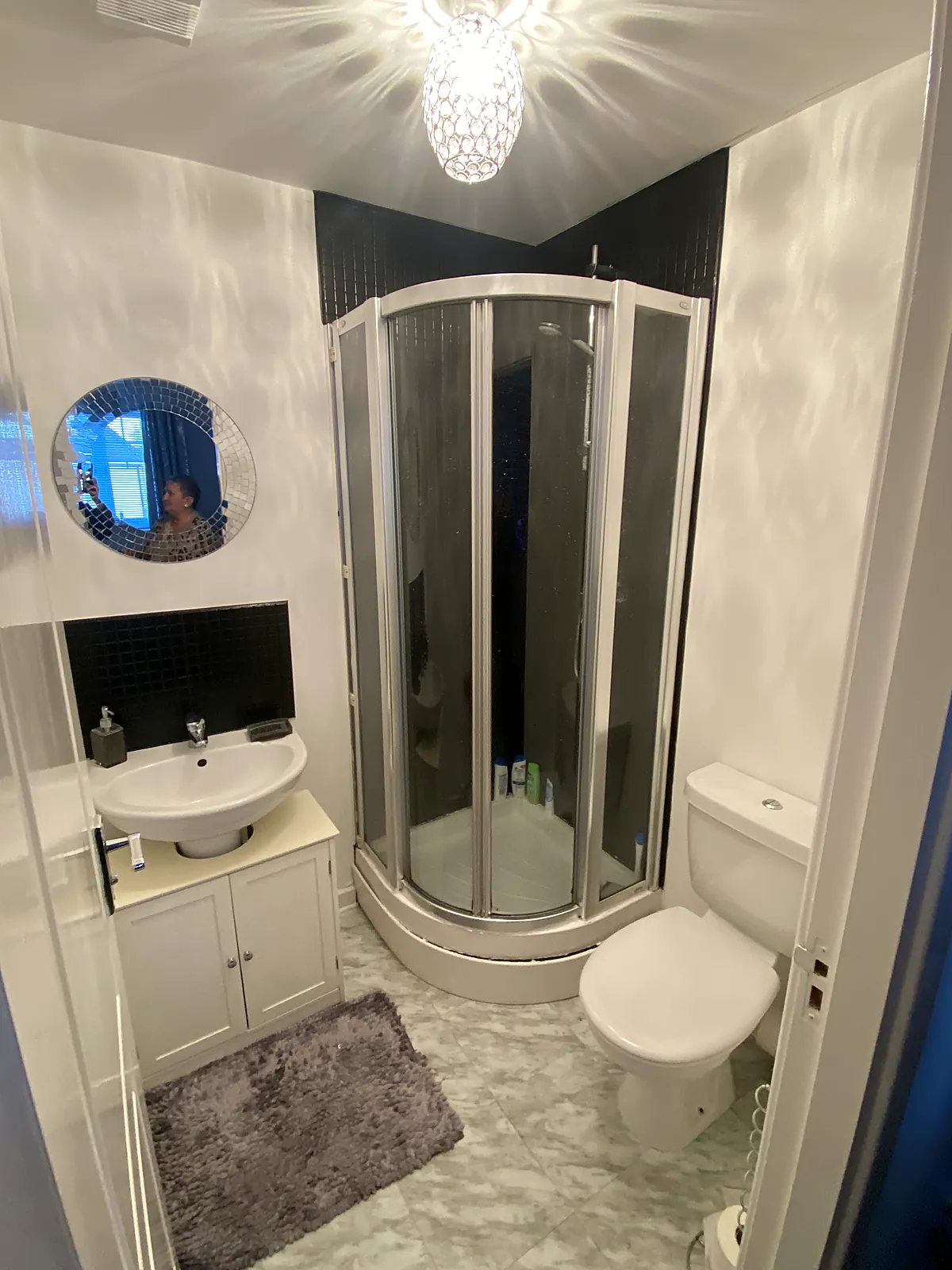 Bathroom with an illuminated round mirror, ceiling pendant and shower enclosure