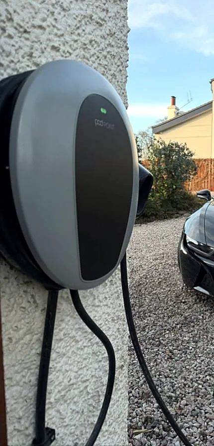 Pod Point EV charge point installed on a rendered house wall in Glasgow with the charging cable coiled