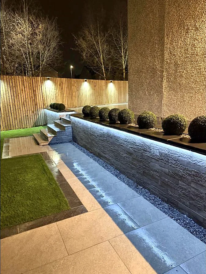 Garden at night lit by recessed wall lighting, fence lights and planted bed lighting in Glasgow