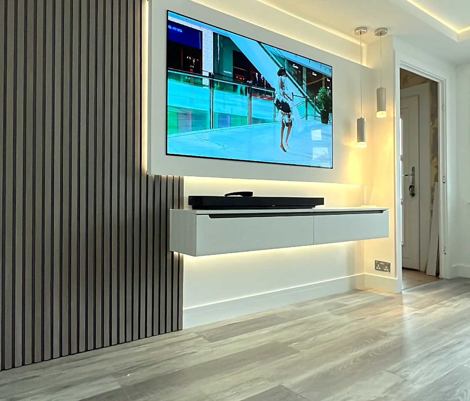 Slatted timber media wall with wall-mounted TV, floating unit and concealed LED lighting in a Glasgow living room