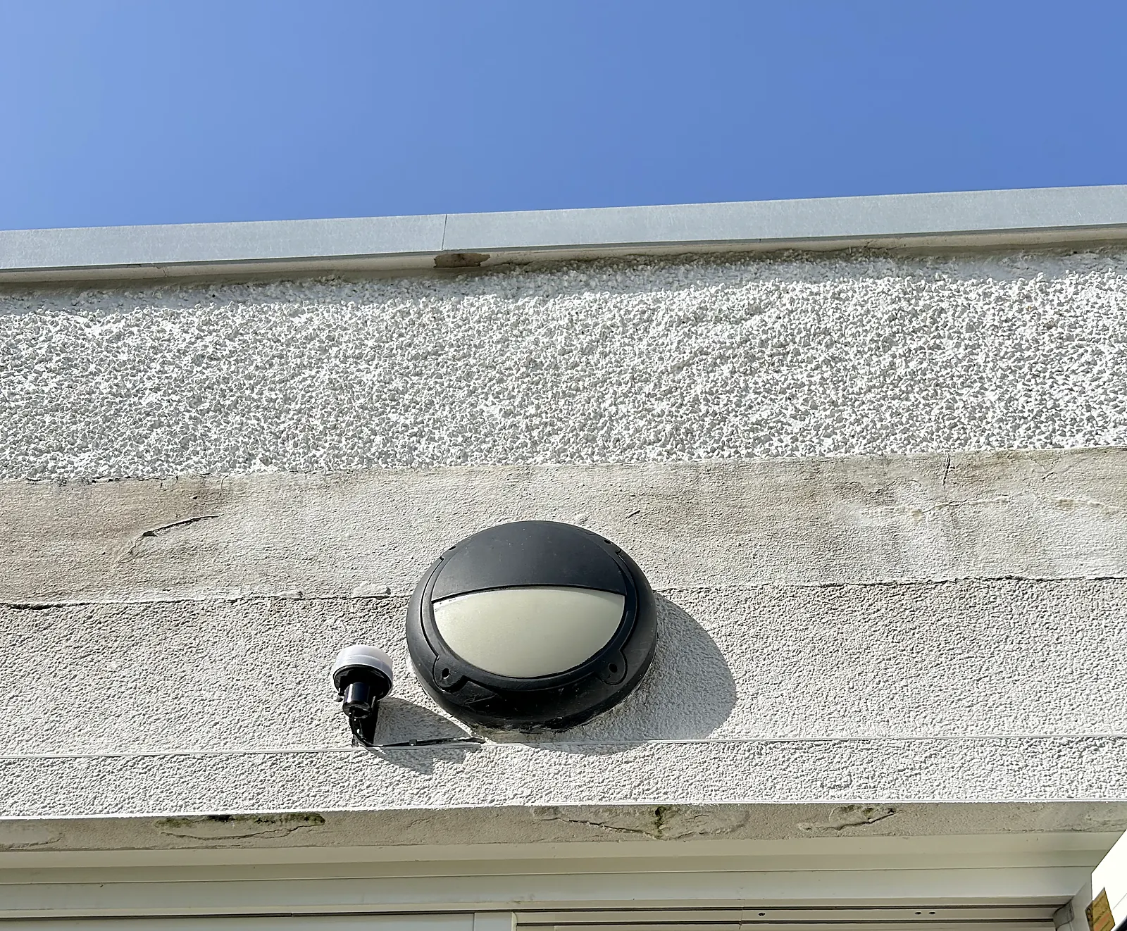Exterior bulkhead wall light installed on a rendered house elevation