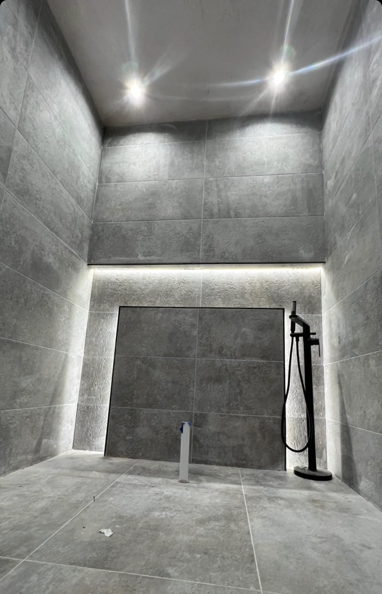 Tiled bathroom with a concealed backlit recess and ceiling downlights, lighting installed and wired by MMM Electrical