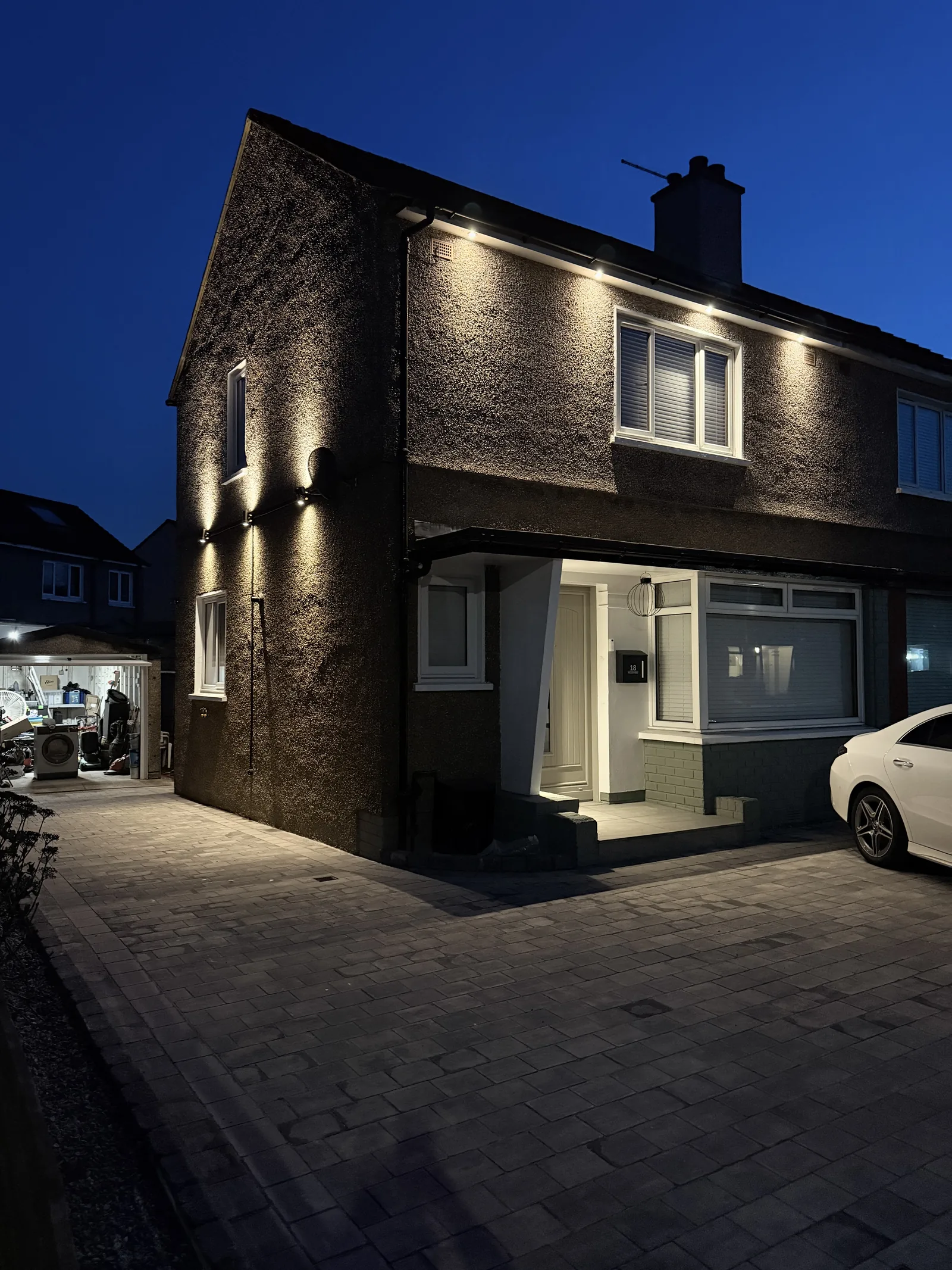 Semi-detached Glasgow house at dusk with soffit downlights and wall uplighters installed and wired by MMM Electrical